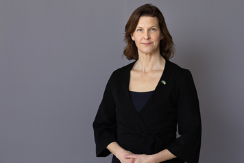 Halvkroppsbild på Nina Larsson, tagen inomhus mot grå bakgrund.