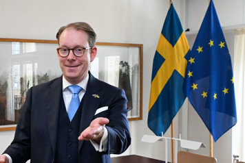 欧盟外交部长托比亚斯·比尔斯特罗姆·斯特拉尔·弗拉姆福尔（Tobias Billström stár framför EU:s och Sveriges flaga）