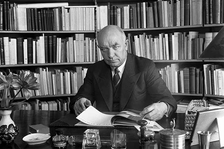 Per Albin Hansson vid ett skrivbord. I bakgrunden en bokhylla.