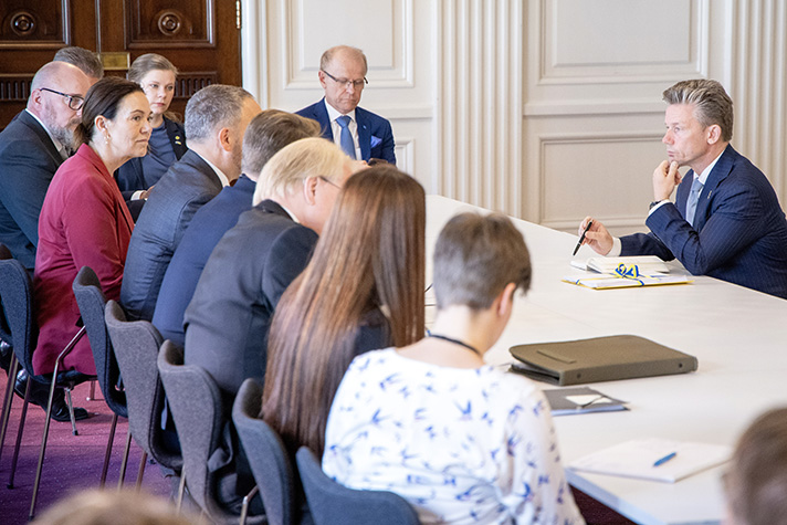 Personer sitter runt ett mötesbord.