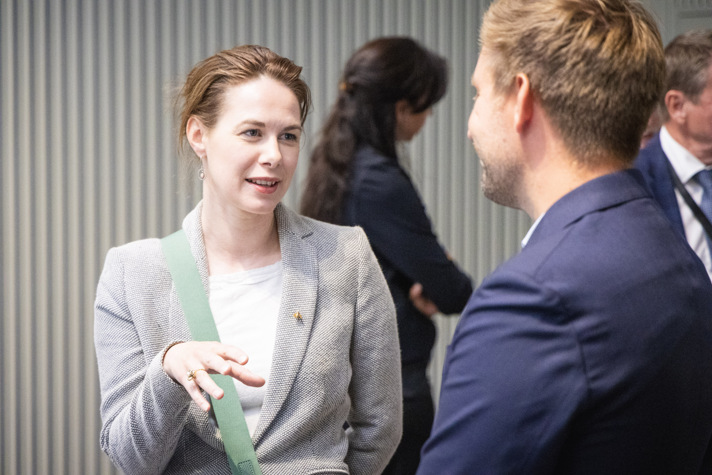 En kvinna står och pratar med en annan företagsrepresentant.