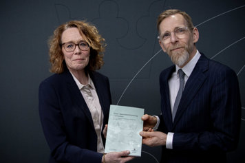 Maria Landgren räcker över utredningen till Jakob Forssmed. Båda ler mot kameran.