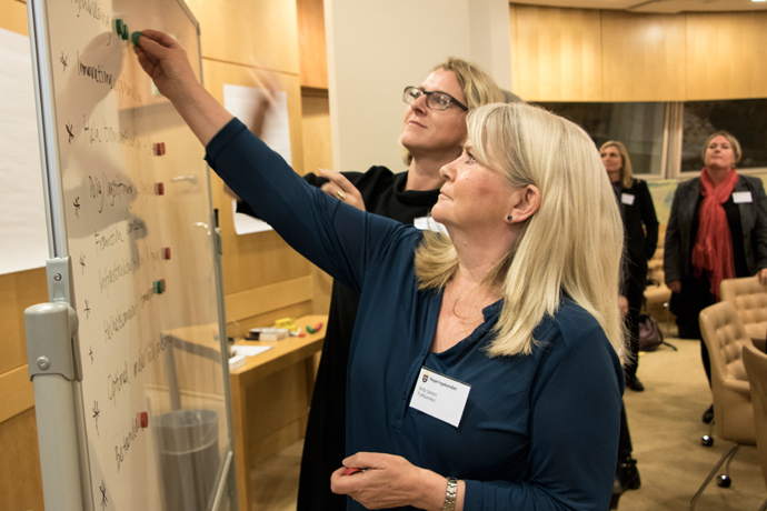 Två kvinnor står och skriver på en whiteboardtavla