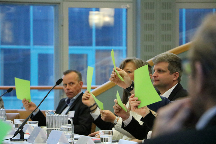 Flera personer sitter runt ett bord och håller upp gröna lappar