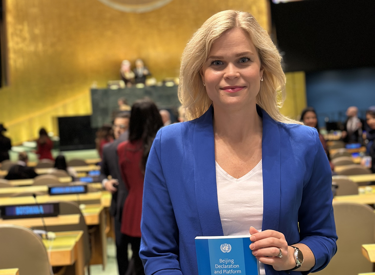 Jämställdhets- och arbetslivsminister Paulina Brandberg står i en lokal. I bakgrunden syns flera personer.