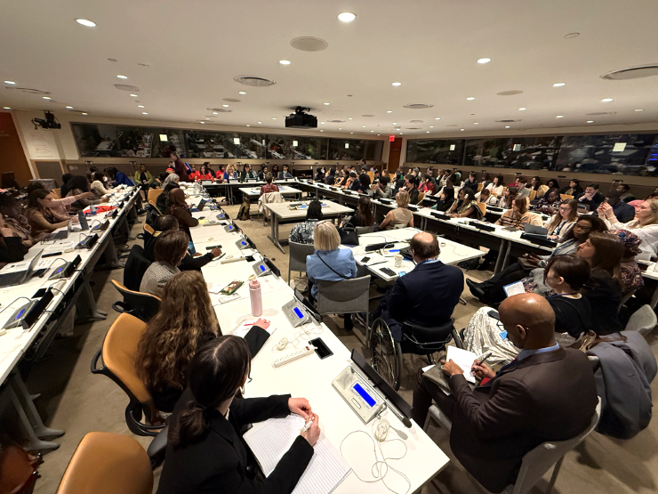 Flera personer sitter i en stor sal som är fullsatt. Längst fram sitter några personer och håller i mötet.