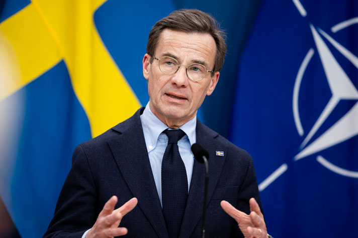 Statsminister Ulf Kristersson avbildad i halvfigur i en talarstol.