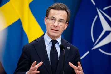 Statsminister Ulf Kristersson avbildad i halvfigur i en talarstol.