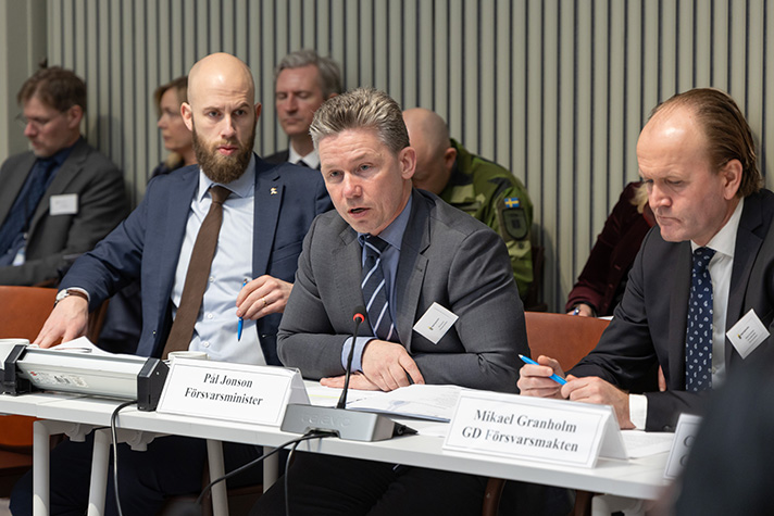 Pål Jonson har tagit ordet. Carl-Oskar Bohlin sitter snett bakom och lyssnar med Mikael Grönholm sitter framåtlutad och lyssnar.  