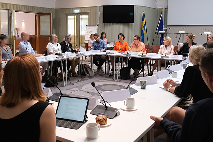 Foto från konferensrum med flera personer vid bord som står i fyrkant