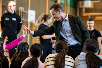Statsminister Ulf Kristersson  gör "high five" med barn i Hovsjö basketförening