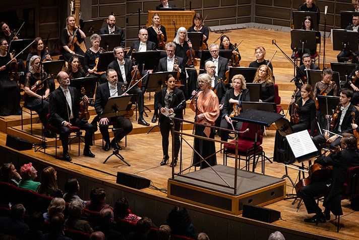 Kulturministern och konserthuschefen står på scenen tillsammans med ensemblen.