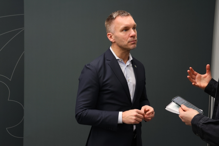 Civilminister Erik Slottner blir intervjuad av journalist framför grå bakgrund.