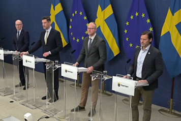 De fyra medverkande står bakom var sin talarstol. Det är flaggor i fonden.