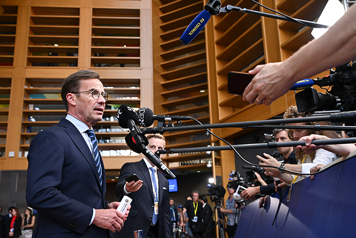 Ulf Kristersson står framför flera mikrofoner som sträcks fram av journalister.