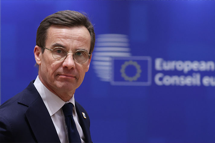 Ulf Kristersson mot en blå fotovägg.