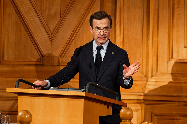 Ulf Kristersson står i en talarstol i förstakammarsalen i riksdagen.