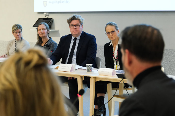 Bild på justitieminister Gunnar Strömmer med tjänstemän från departementet i möteslokal.