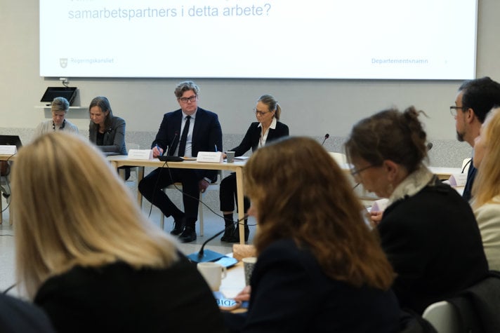Bild på justitieminister Gunnar Strömmer i möte med representanter från flera myndigheter, forskare och kommuner i möteslokal.