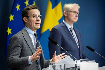 tatsminister Ulf Kristersson och Mikael Tofvesson i var sin talarstol framför en fond med svenska flaggor