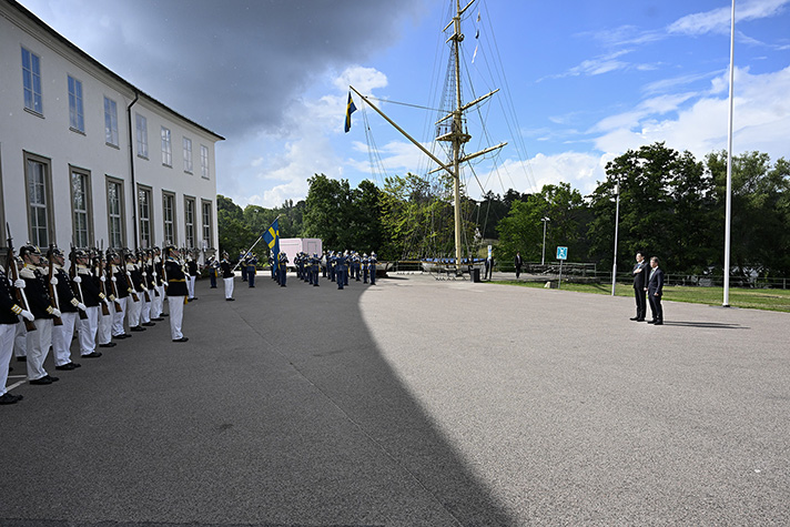 Ministrarna stående utomhus framför hedersvakten.
