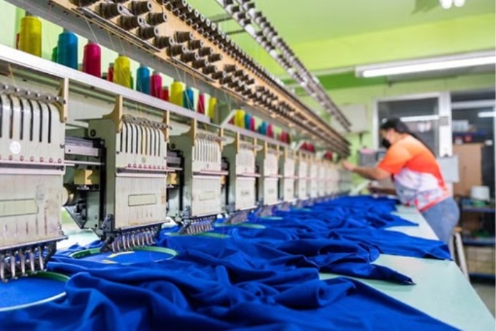 Person arbetar med att producera textilier vid en arbetsbänk.