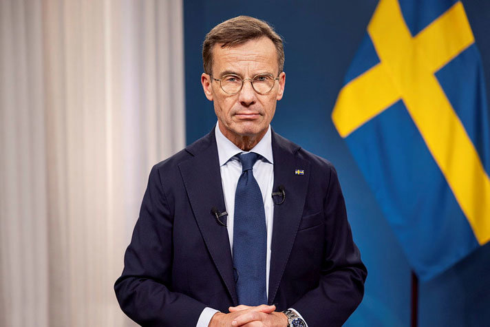Statsminister Ulf Kristersson i halvfigur framför drapering