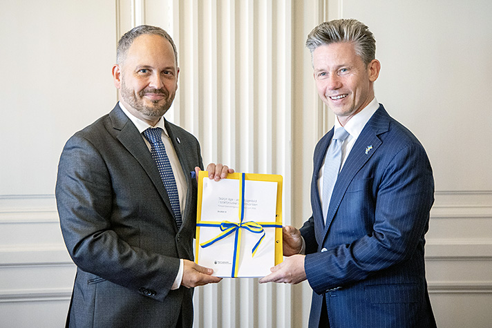 Ordförande och försvarsministern håller i delrapporten.