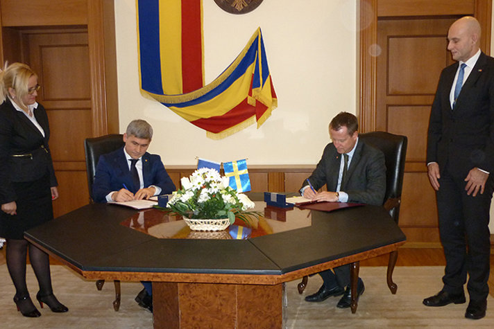 Två personer vid ett bord undertecknar ett avtal