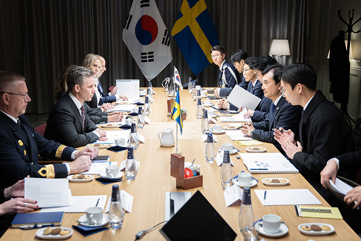 Pål Jonson sitter mittemot Sydkoreas försvarsminister Ahn Gyu-back vid ett långbord tillsammans med representanter från bägge länder. I bakgrunden syns Sveriges och Sydkoreas flagga.