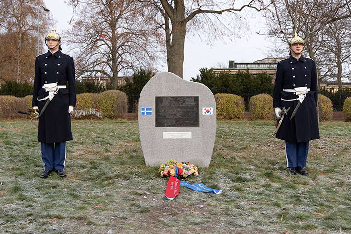 Mellan två svenska hedersvakter står minnesstenen över den svenska insatsen under Koreakriget. En krans ligger nedlagd framför stenen.