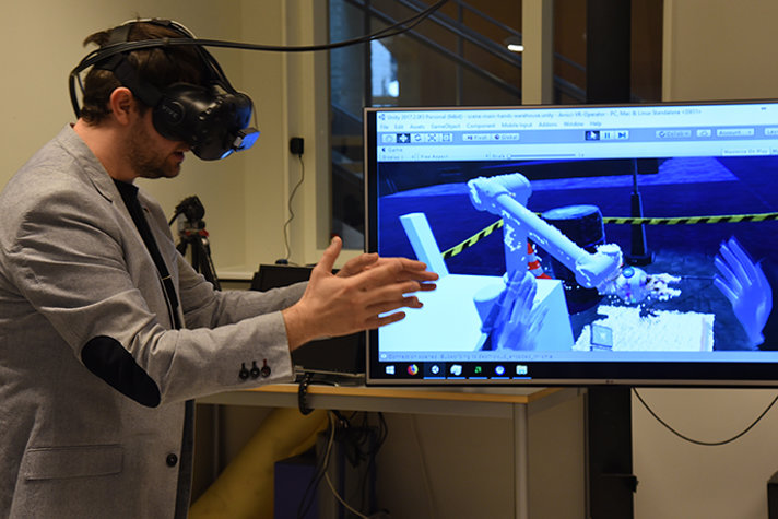 En person står med VR-glasögon på sig och rör händerna framför en skärm