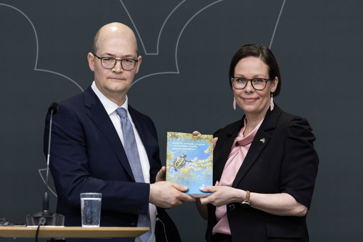 En man och en kvinna håller upp ett betänkande.