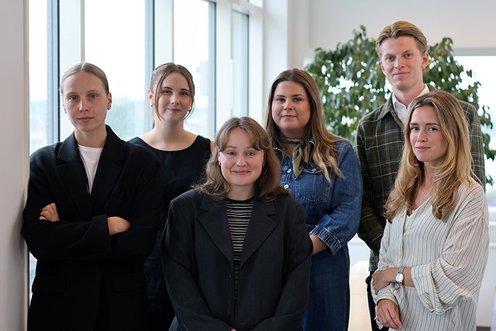 Fem kvinnor och en man står framför ett fönster.