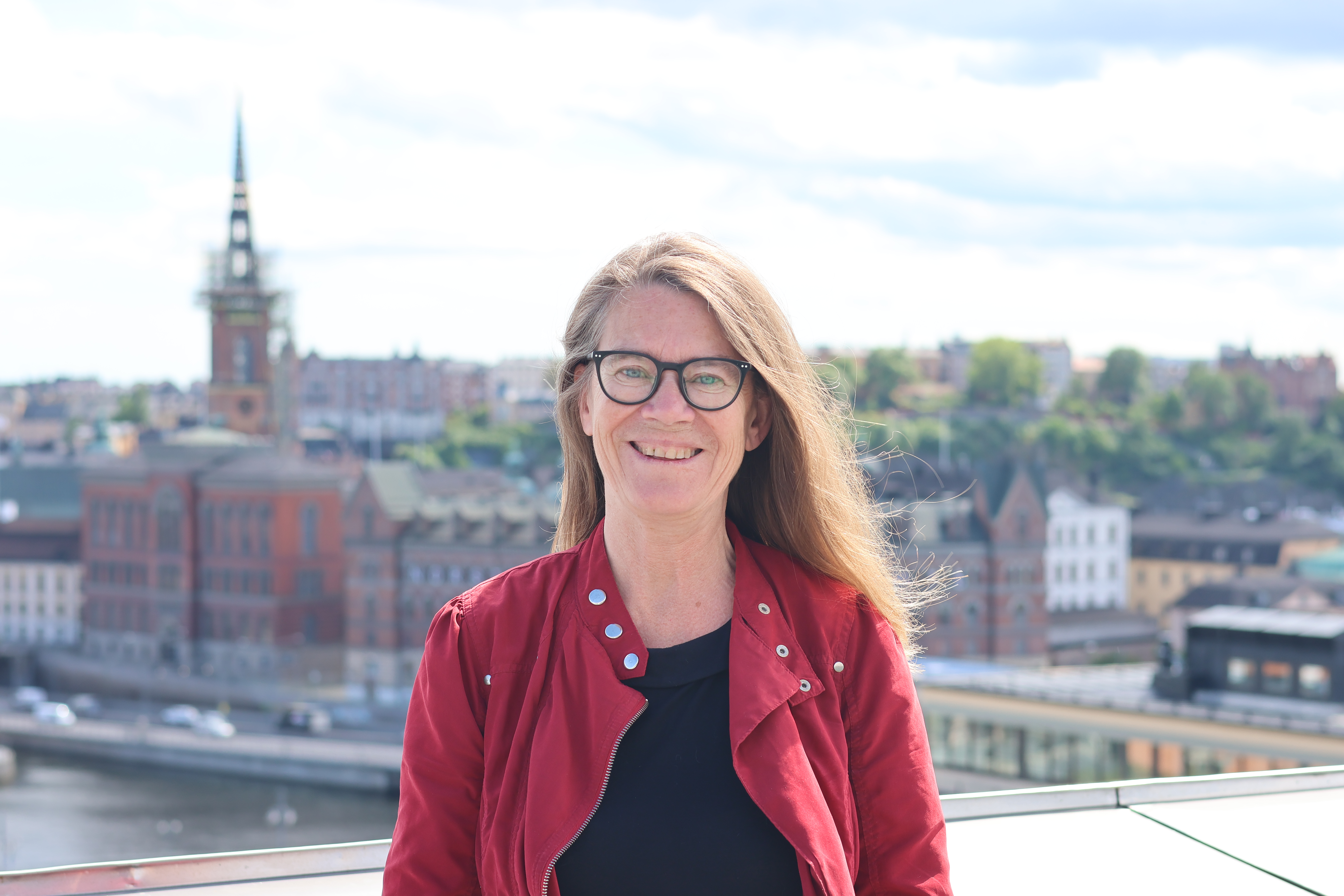 Marita står på en takterrass. I bakgrunden syns Stockholms innerstad.