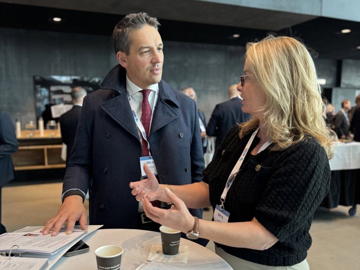 Ministrarna står vid ett ståbord i en stor lokal och diskuterar.