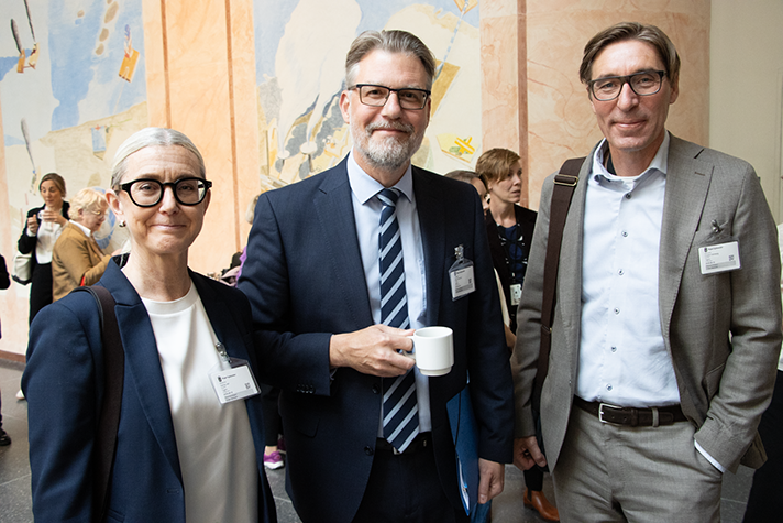 Tre personer står bredvid varandra och tittar framåt.