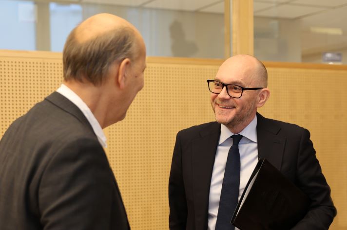 Arbetsmarknadsminister står och pratar med en av deltagarna under mötet med Arbetsmarknadspolitiska rådet