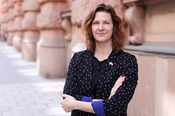 Porträttbild på Nina Larsson, fotad utomhus. Nina Larsson ser nöjd ut och håller armarna i kors.