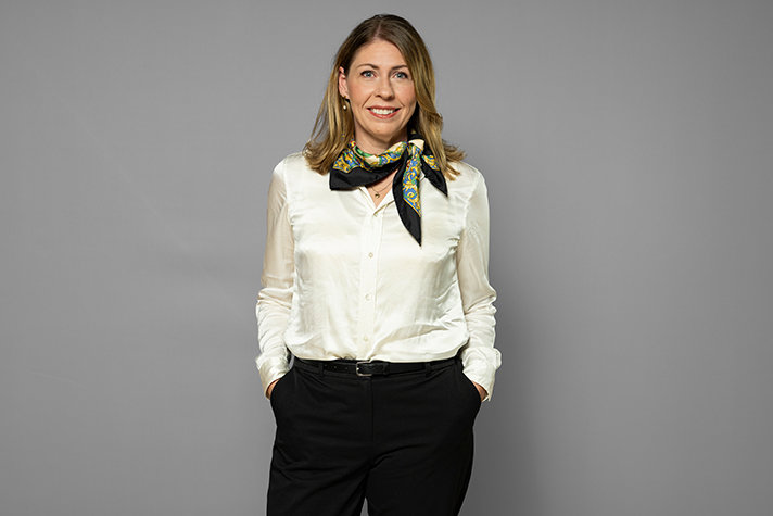 Elisabet Lann ler och tittar in i kameran. Hon bär en vit blus.