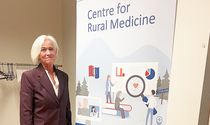 Acko Ankarberg Johansson står vid en skylt där det står Centre for Rural Medicine