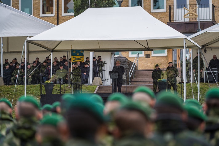 Peter Hultqvist i talarstol utomhus med publik i militärkläder.