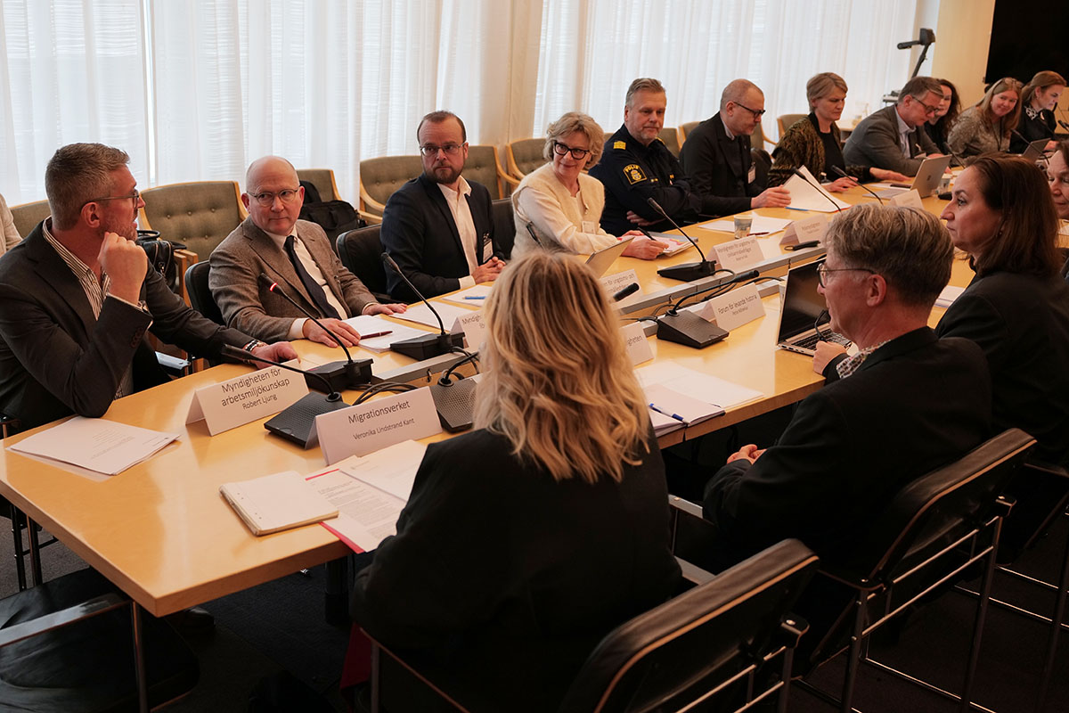 Flera personer sitter runt ett stort bord i ett sammanträdesrum.