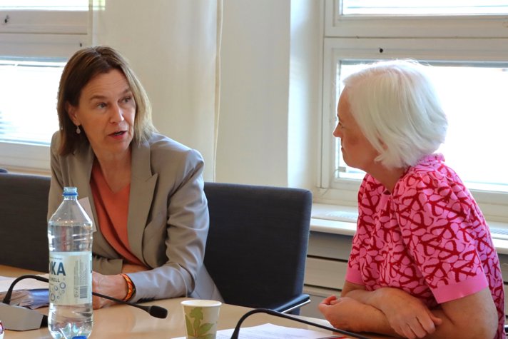 Foto på Olivia Wigzell och Acko Ankarberg Johansson sitter vid ett konferensbord.