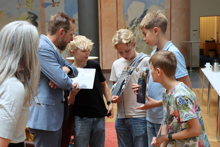 Fyra pojkar visar upp sina foton för socialminister Jakob Forssmed.