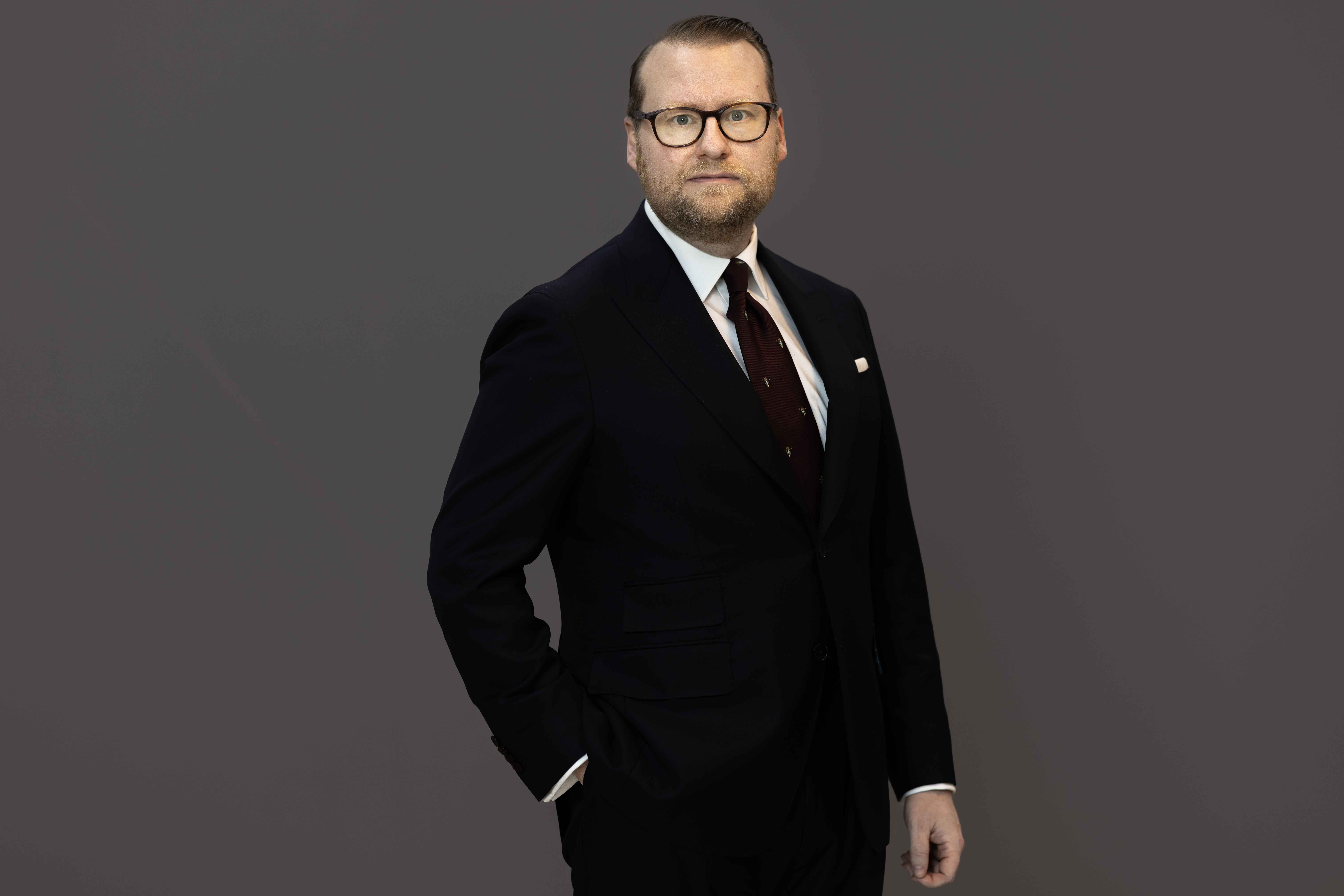 Simon Westberg, klädd i kostym står framför en grå bakgrund.