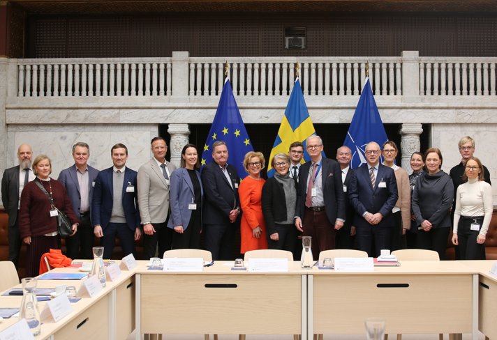 En gruppbild i ett stort mötesrum. Framför personerna på bilden står bord och namnskyltar.