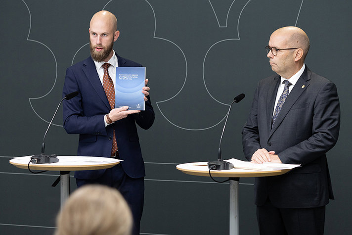 Carl-Oskar Bohlin håller upp utredningen som han precis fått överlämnad till sig av Carl Fredrik Graf som står bredvid Carl-Oskar