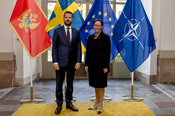Maria Malmer Stenergard och Montenegros president Jakov Milatović står bredvid varandra framför tre flaggor.