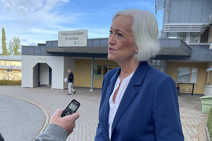 Acko Ankarberg Johansson intervjuas. Bakom henne en skylt där det står Hälsocentralen Kramfors.